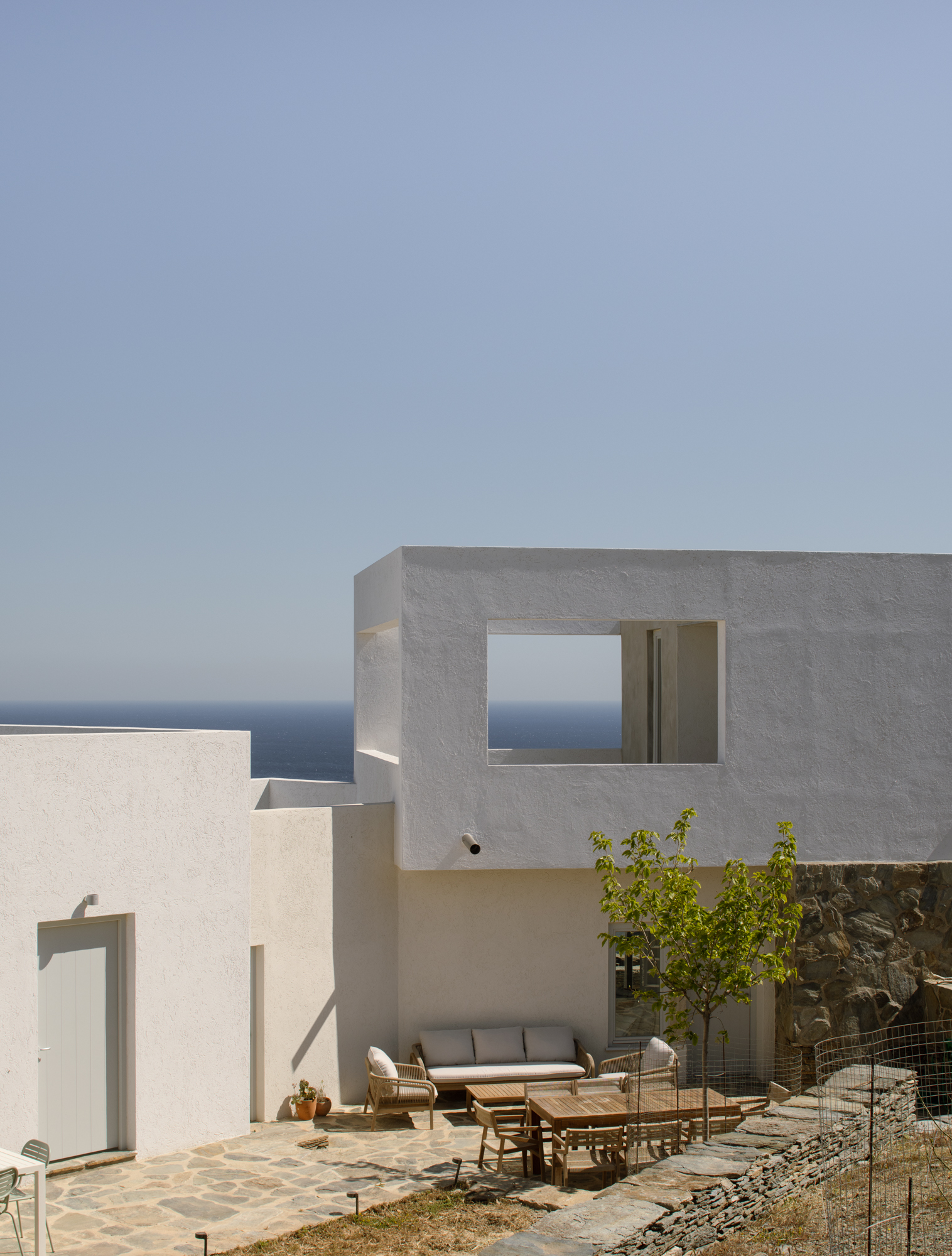 Whitewashed cubic volume with a framed window opening onto the Aegean