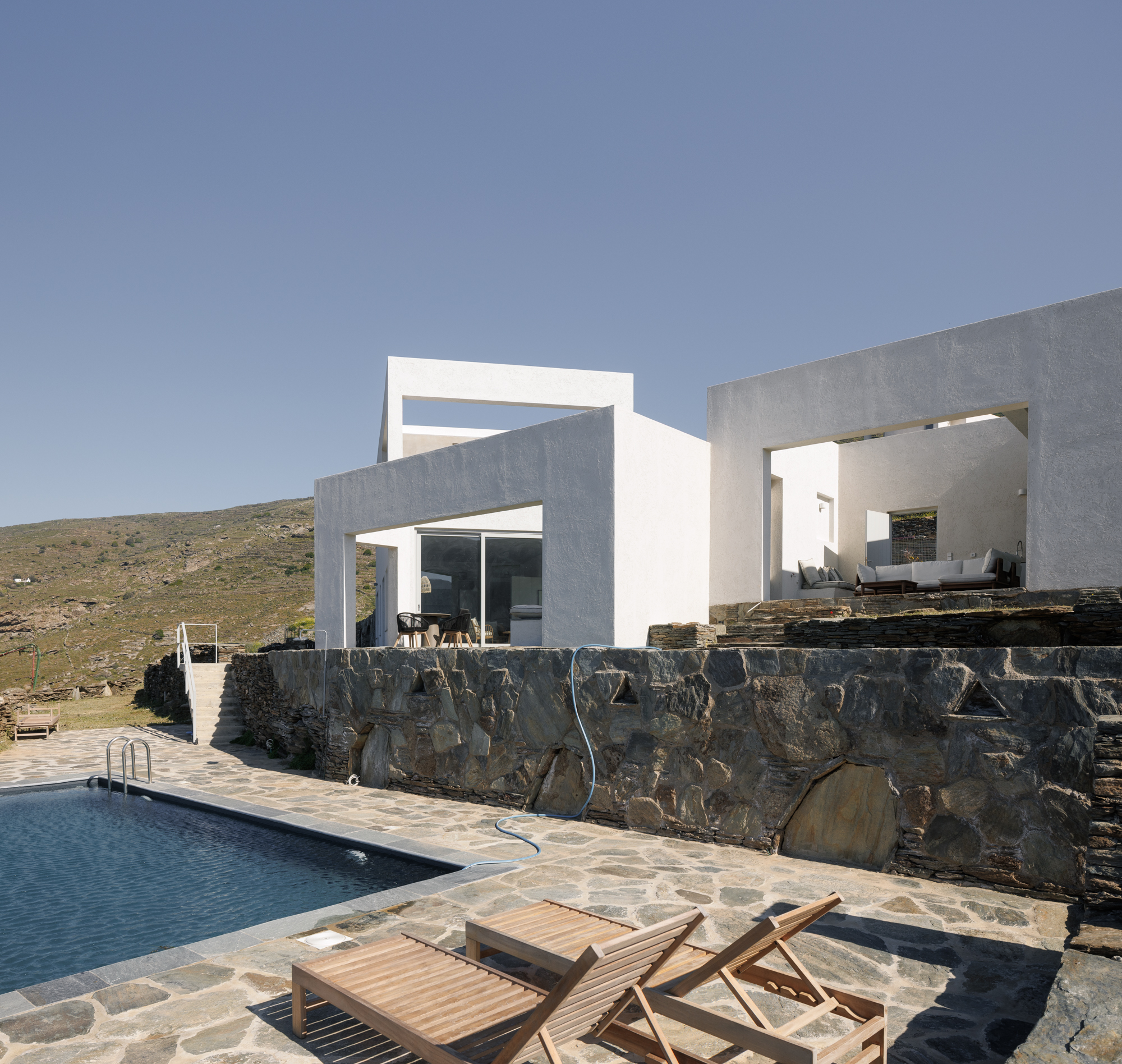 Pool and stone terrace beside the white houses with mountain backdrop