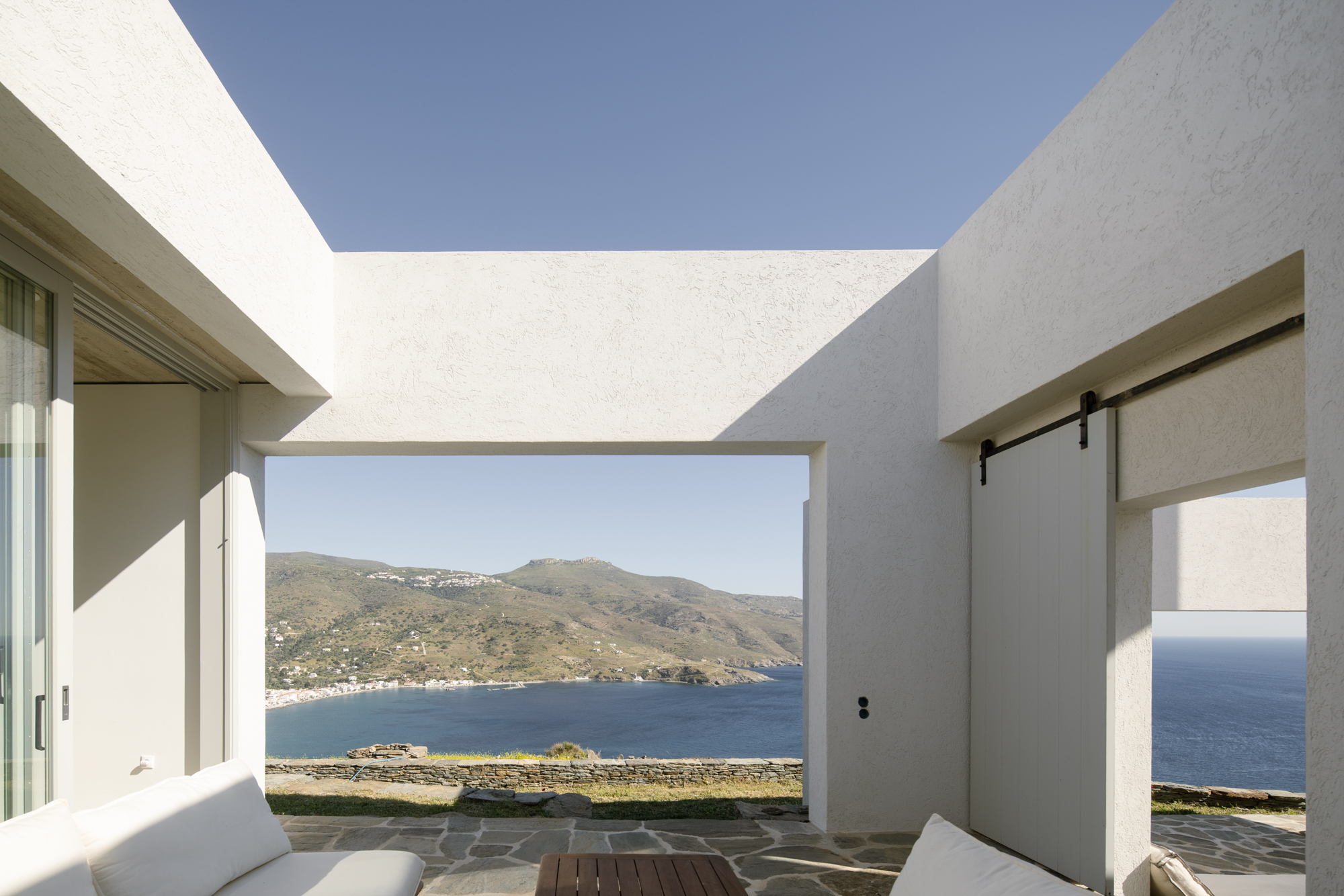 Covered terrace framing Korthi Bay through a sculpted white opening