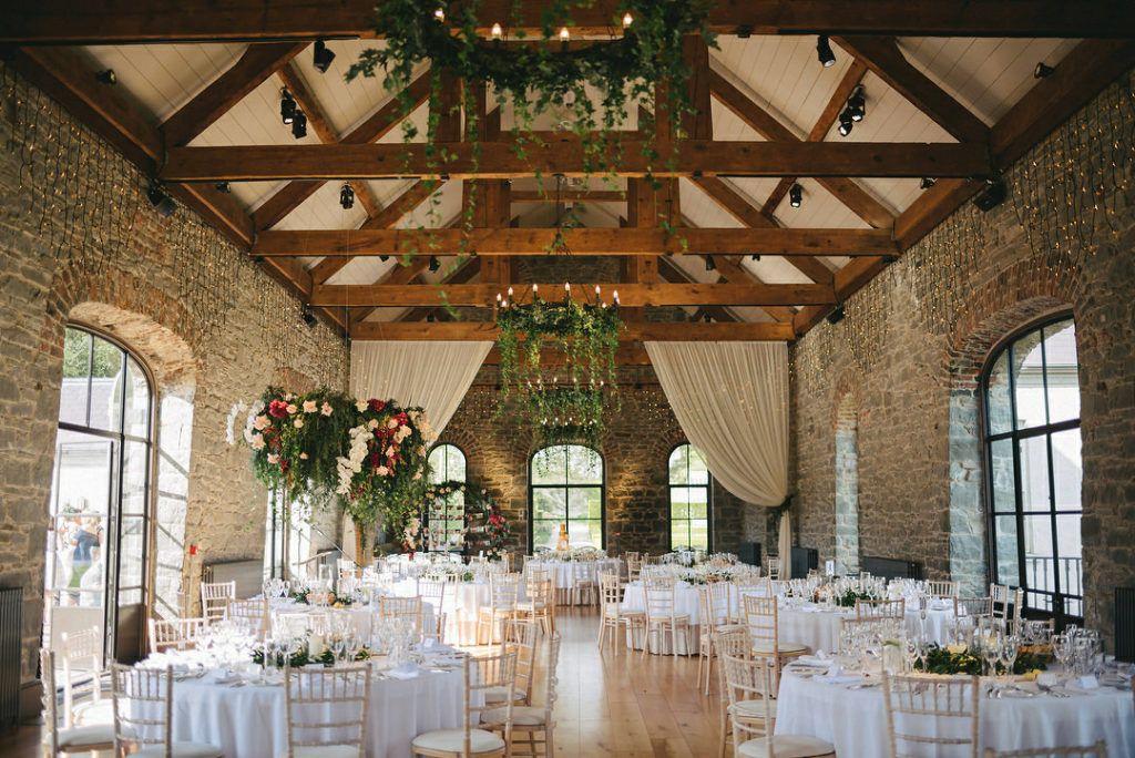 Elegant rustic barn wedding venue with wooden beams and hanging greenery
