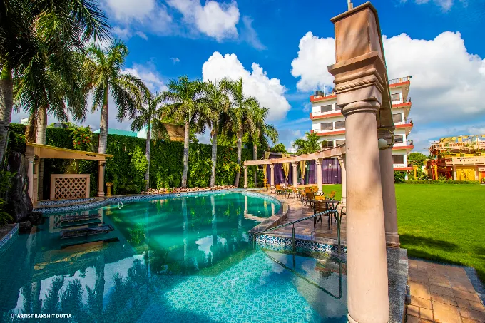 Sparkling swimming pool beside palm trees and the hotel lawns under a blue sky