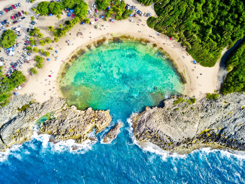Aerial view of Mar Chiquita horseshoe-shaped natural pool with crystal-turquoise water