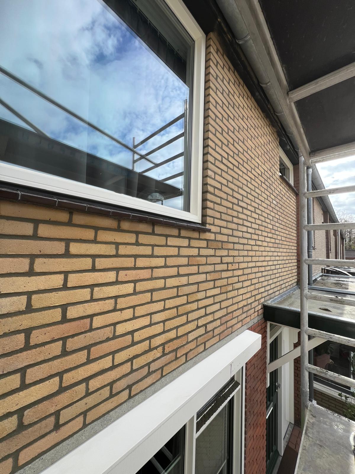 Vers voegwerk op bakstenen muur vanuit steiger — vakkundig afgewerkt