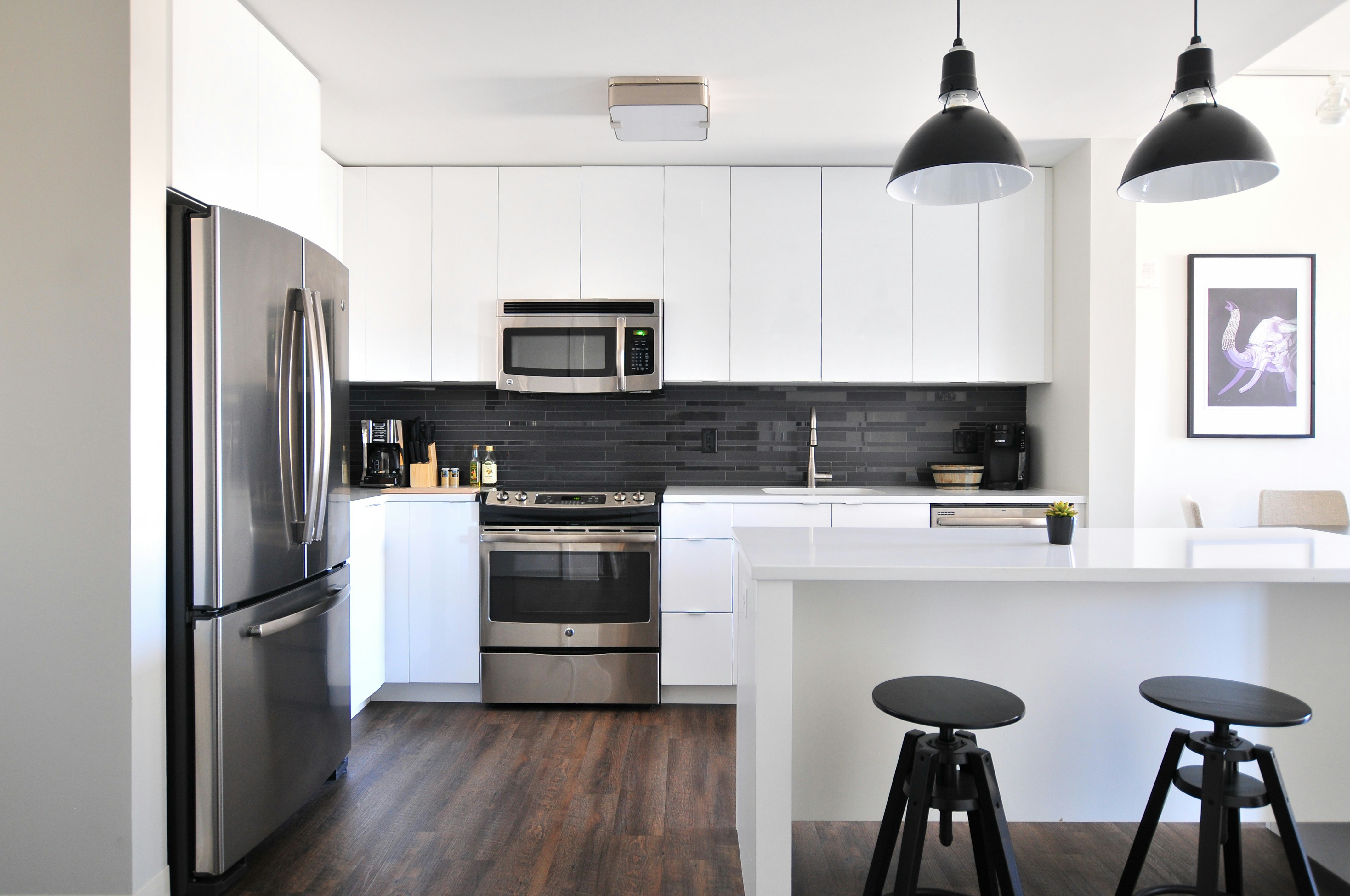 Clean modern kitchen with white cabinets and stainless steel appliances