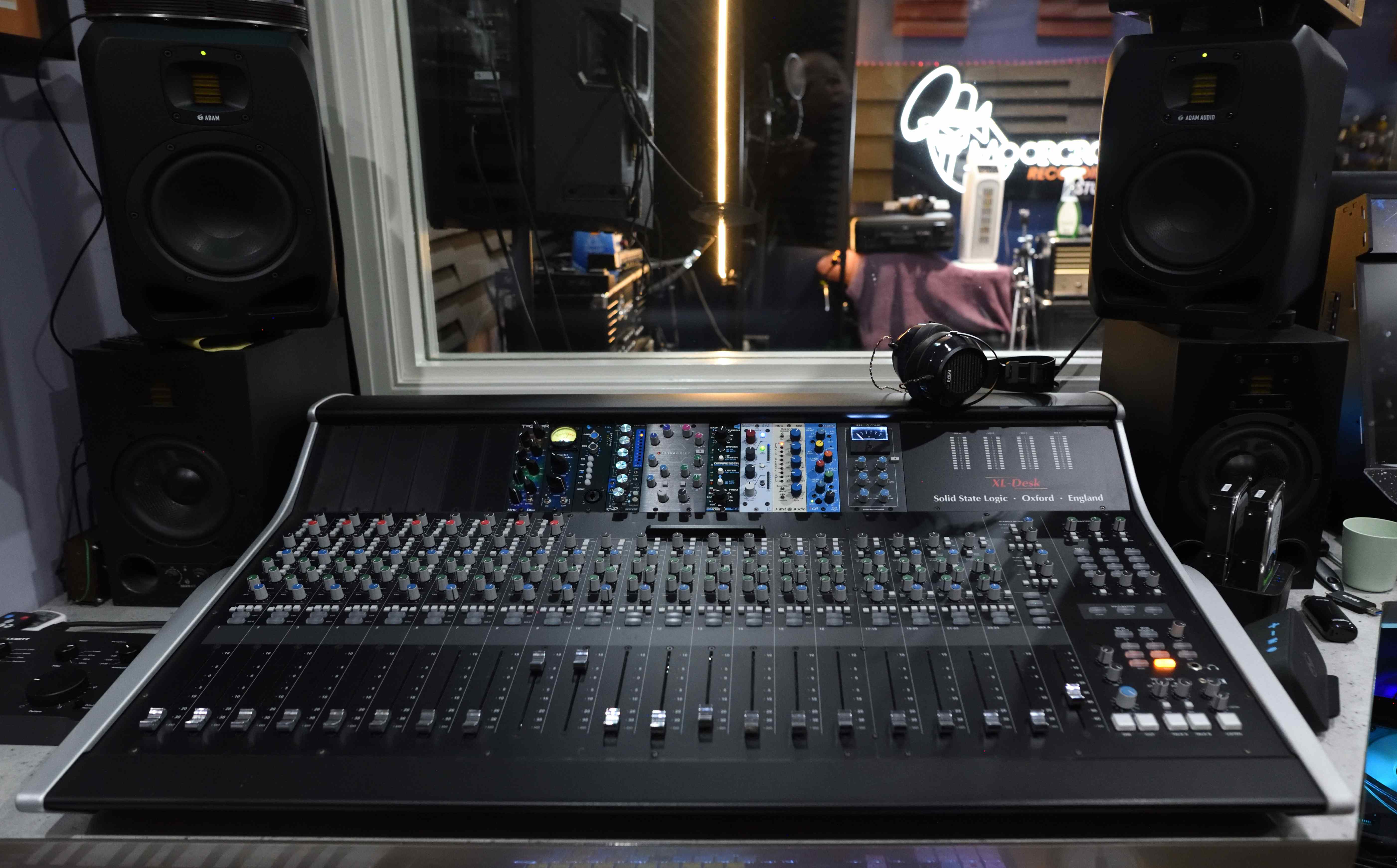 SSL XL-Desk mixing console with ADAM Audio monitors and vocal booth view