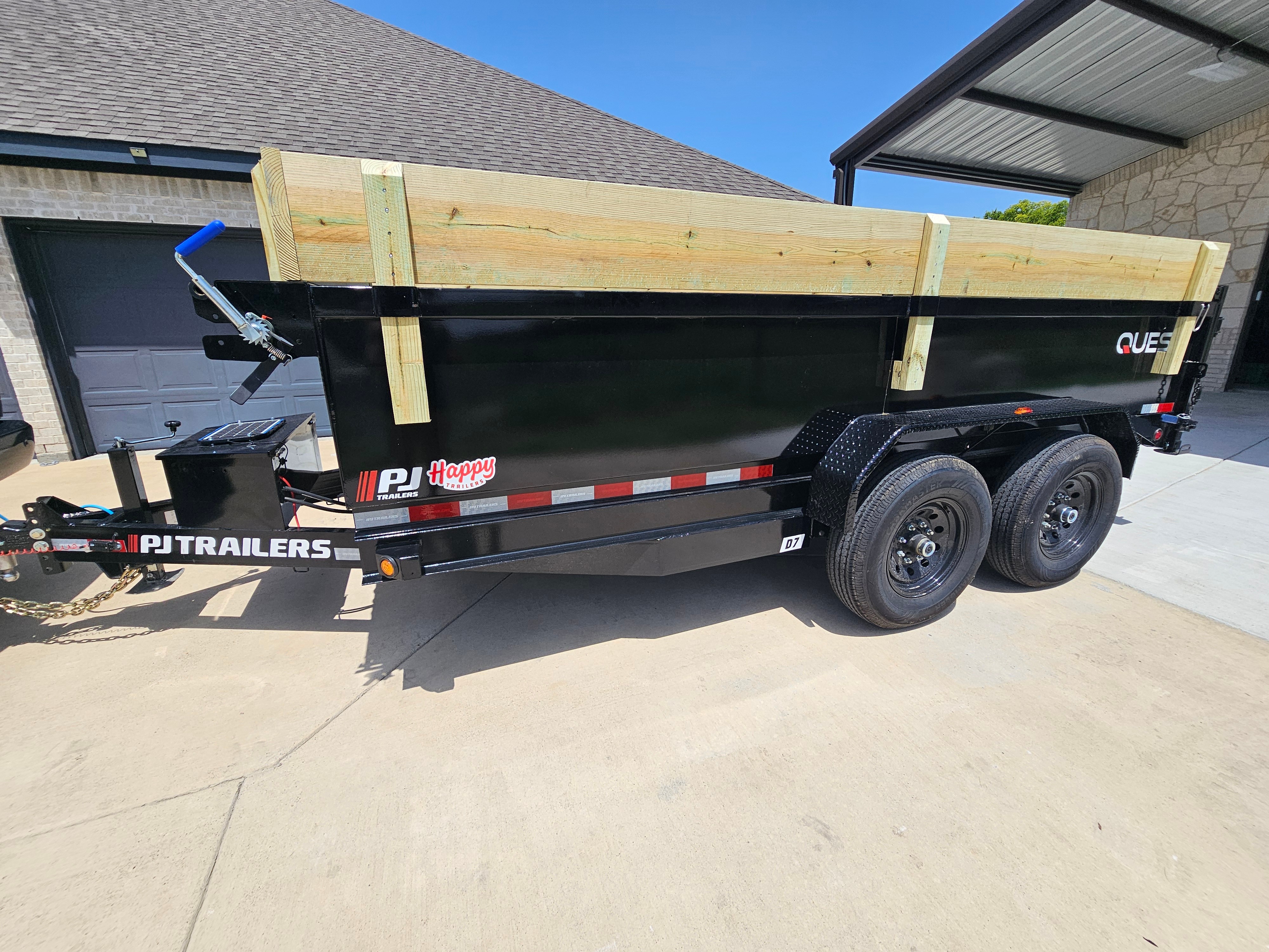PJ Trailers D7 dump trailer side view with wood side extensions under carport