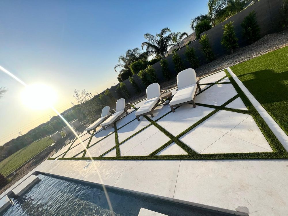 Covered patio outdoor kitchen and lounge overlooking turf backyard