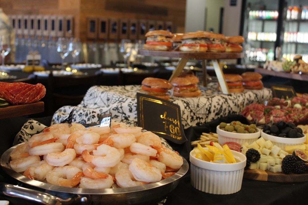 Catered spread with sliders, shrimp, fruit, and charcuterie
