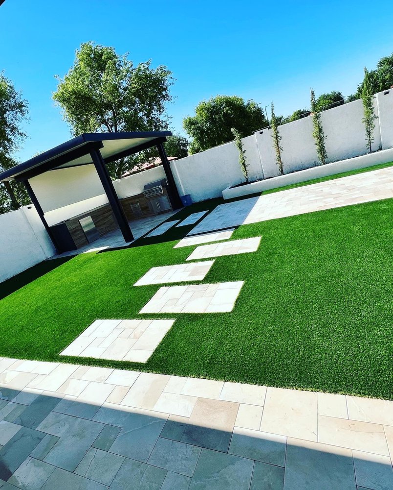 Backyard pergola and outdoor kitchen with turf and stone pavers