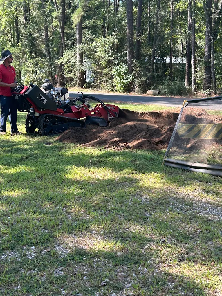 Operator working with track-mounted stump grinder in wooded area