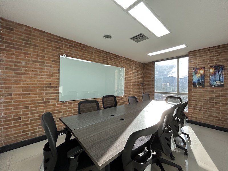 Sala de juntas Oficina 1 con mesa de conferencias, tablero de vidrio y vista a la ciudad en El Poblado, Medellín