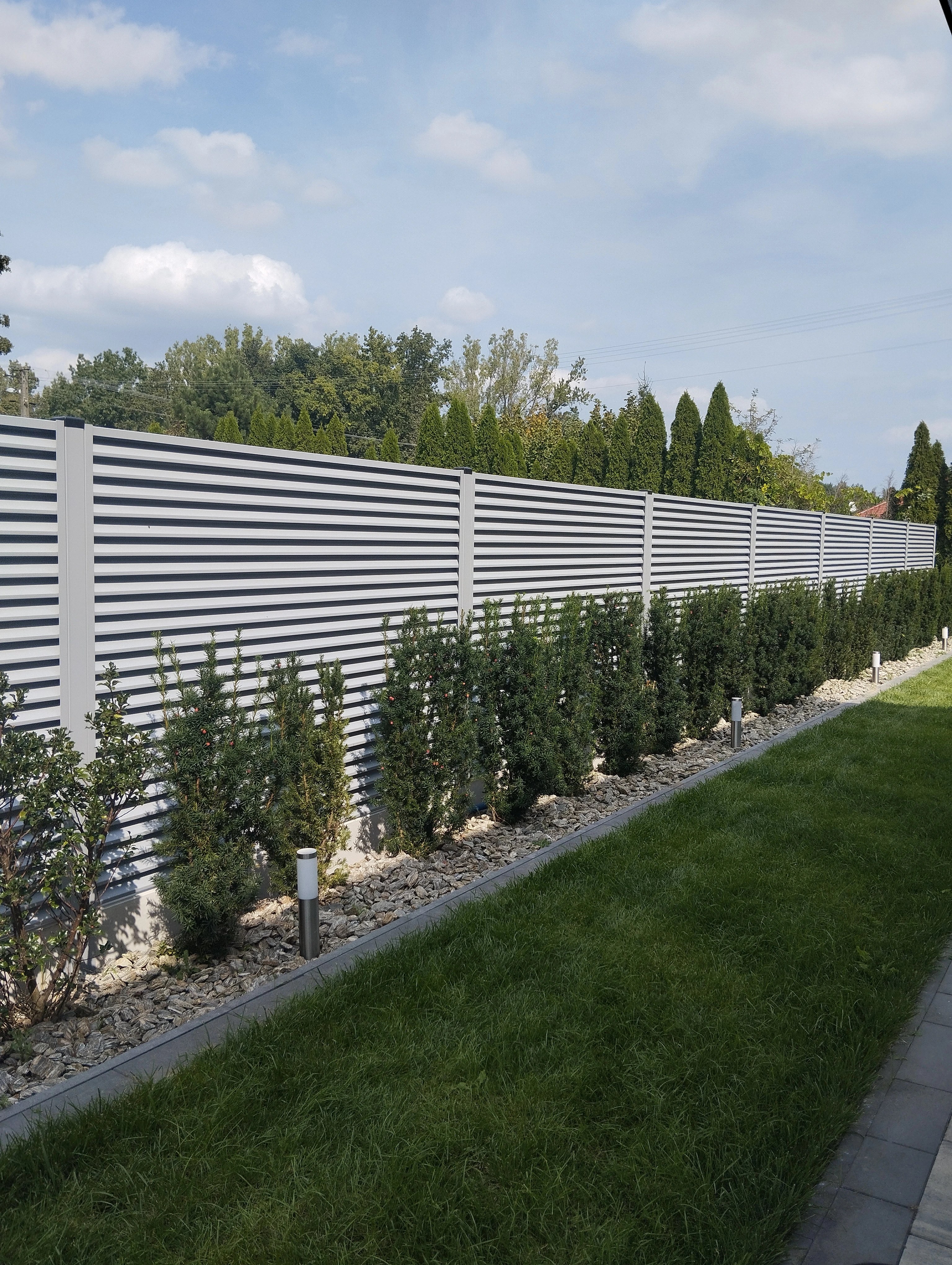 Light gray horizontal slat fence with landscaping