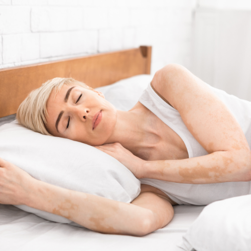 An older woman resting peacefully in bed on white bedding