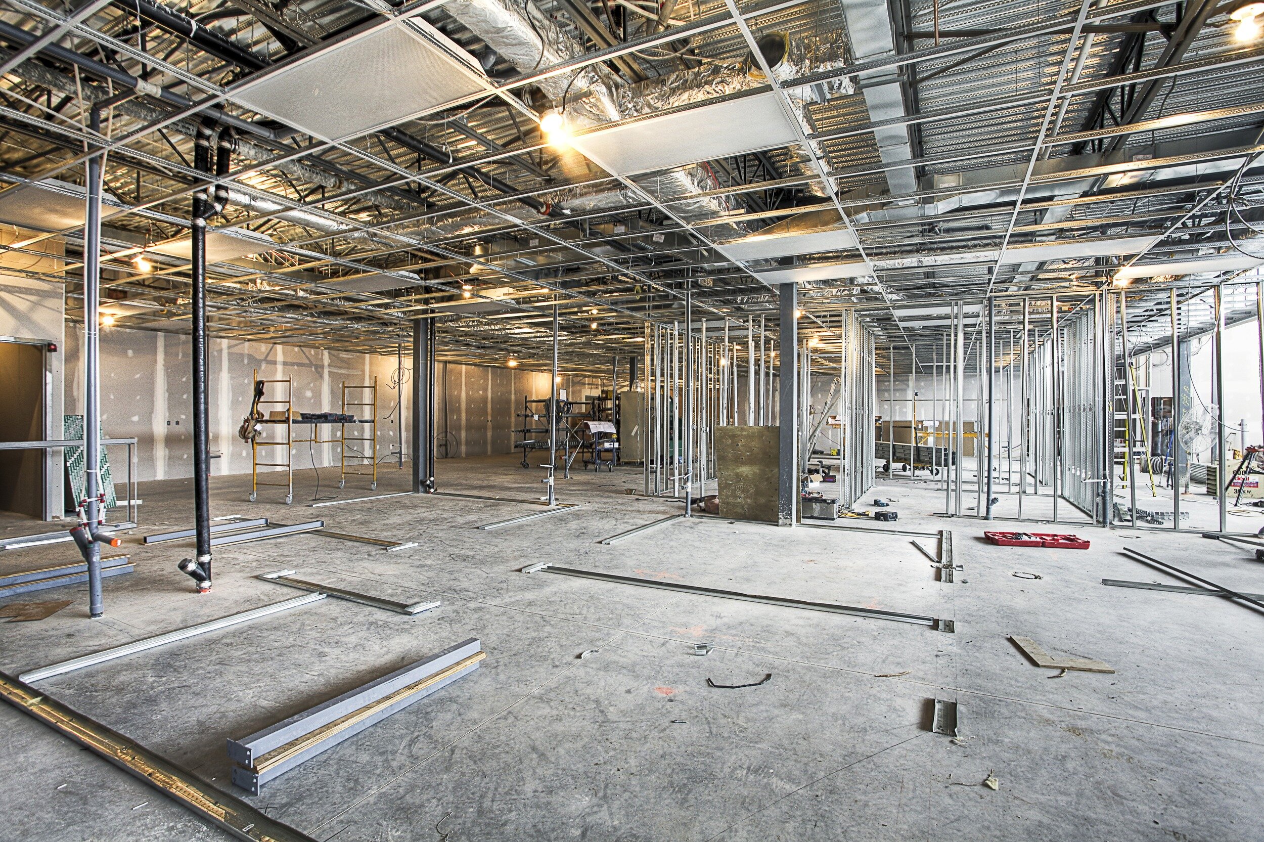Large commercial build-out with steel stud framing, exposed ceiling grid, and concrete floor