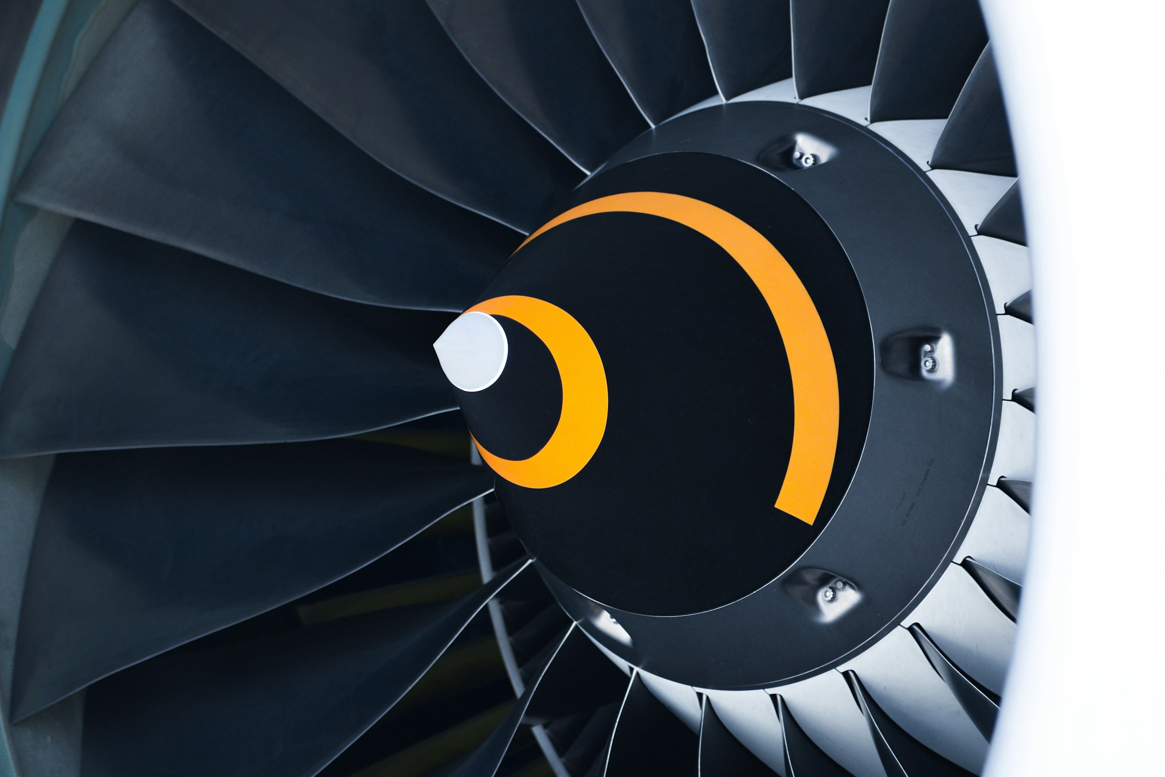 Close-up of jet engine turbine with orange accents representing precision engineering