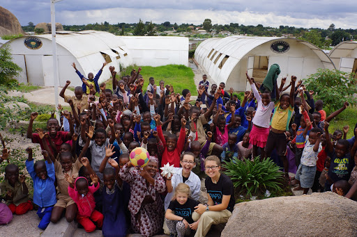 Large crowd of cheering African children with Paper for Water team