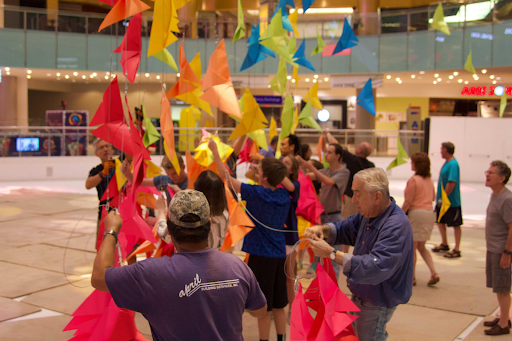 Volunteers hanging colorful origami pieces in the Galleria Dallas
