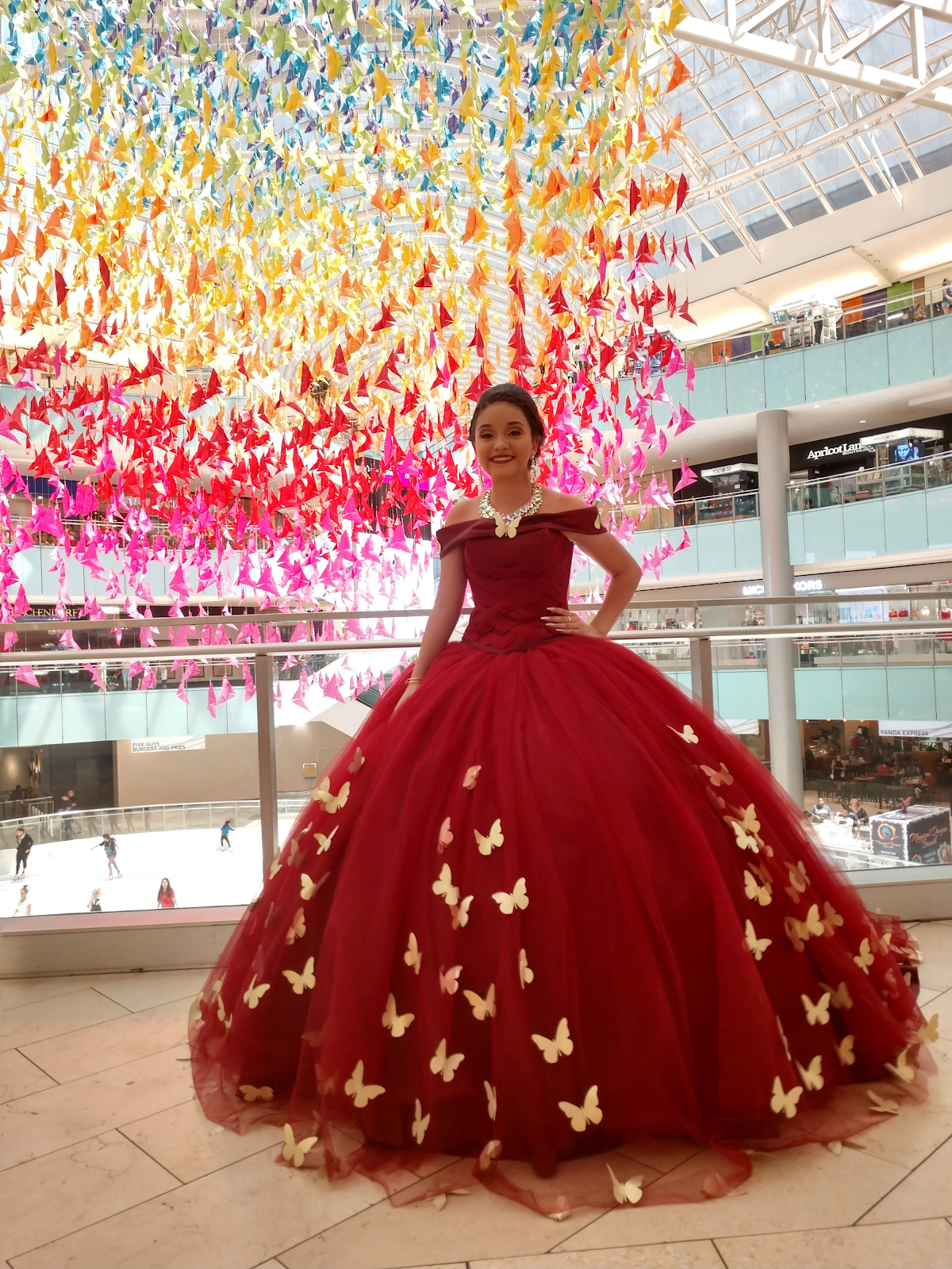 Girl in red ballgown standing under the Fold to Flight butterfly installation