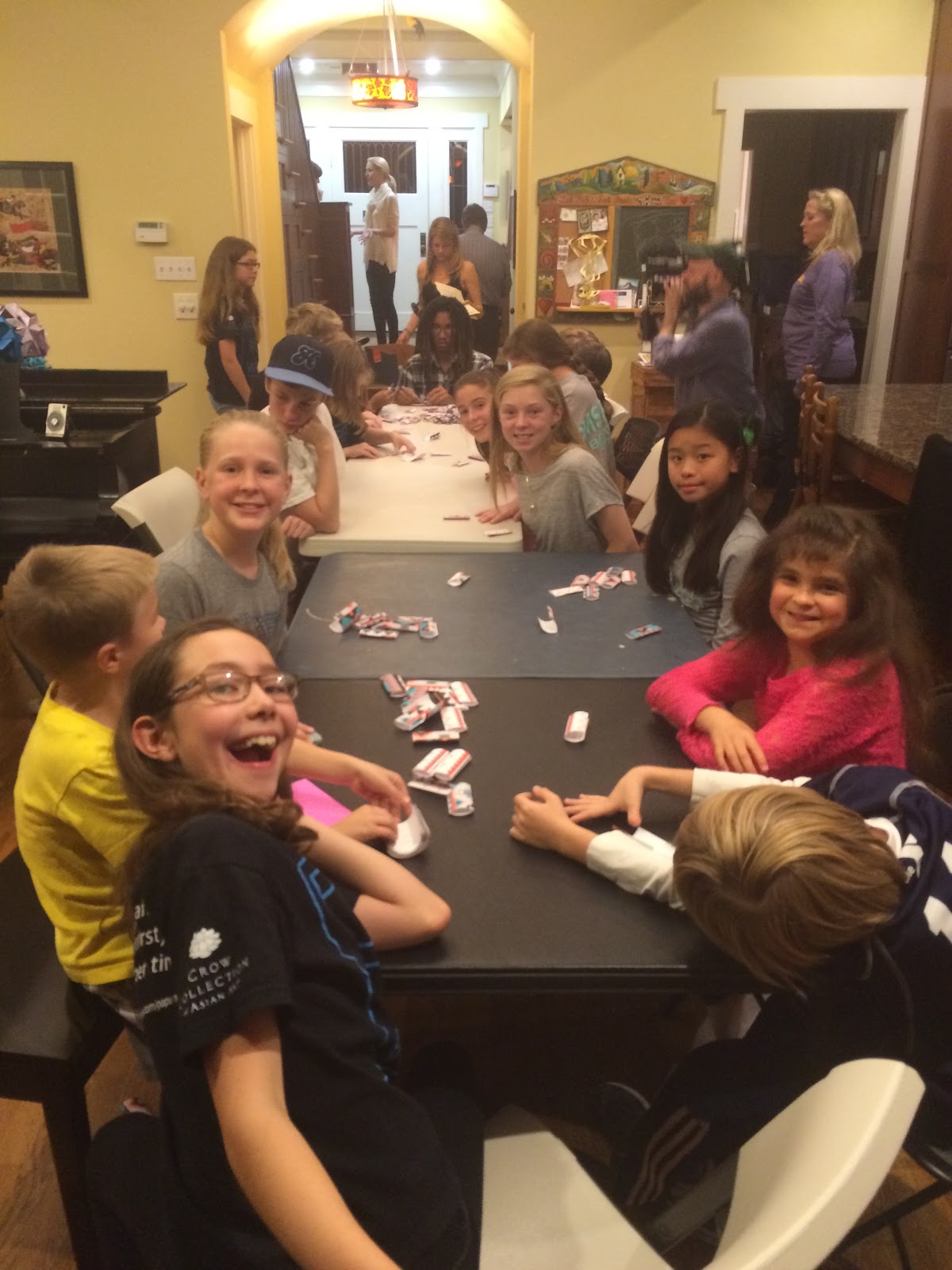 Kids folding origami at tables during a Halo Effect volunteer event