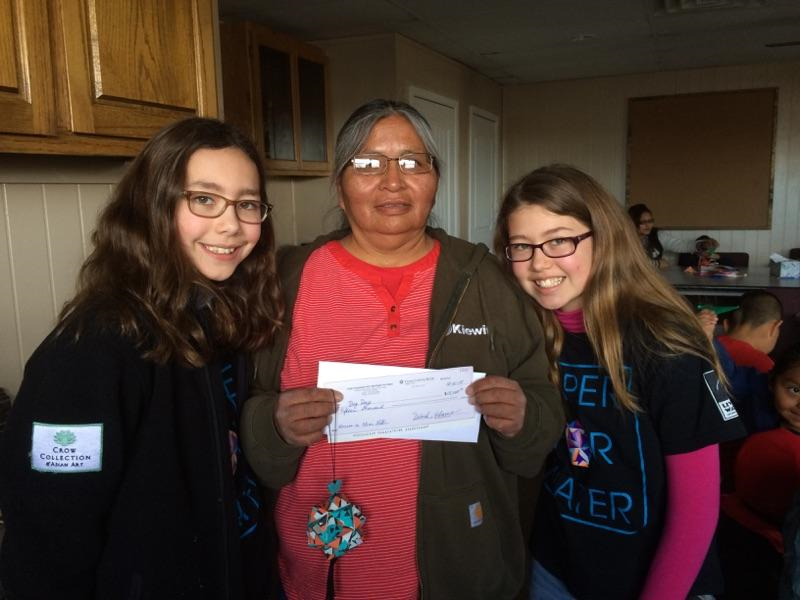 Two girls presenting a check to a Navajo woman