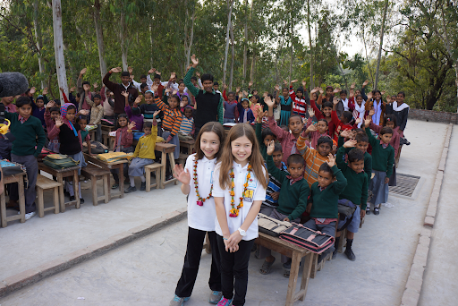 Katherine and Isabelle Adams with garlands in front of Indian schoolchildren