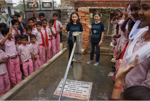 Girls next to a hand-pump water well with Indian schoolchildren