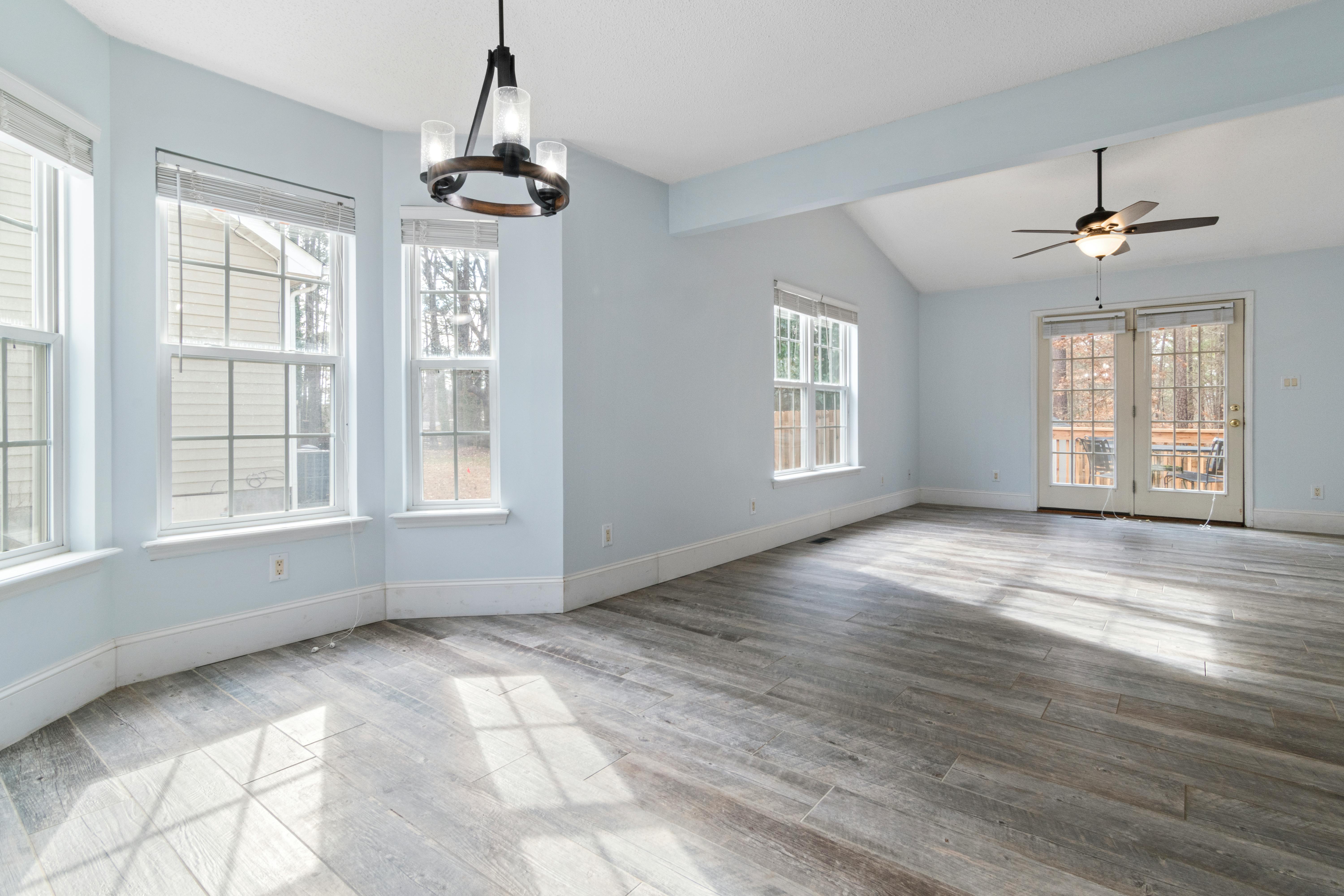 Renovated sunroom with hardwood floors, light blue walls, and large windows