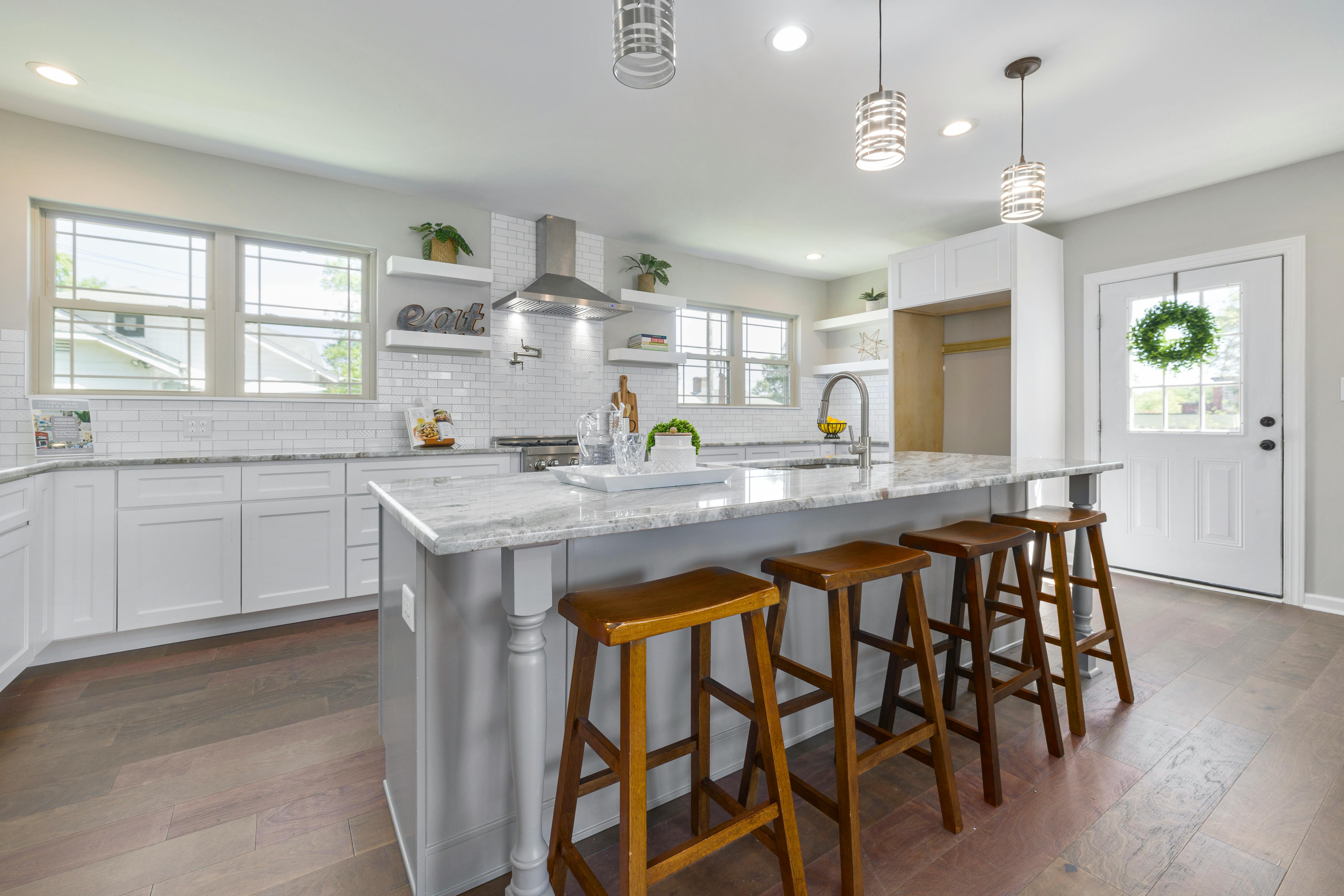 Remodeled white kitchen with marble island and wooden bar stools