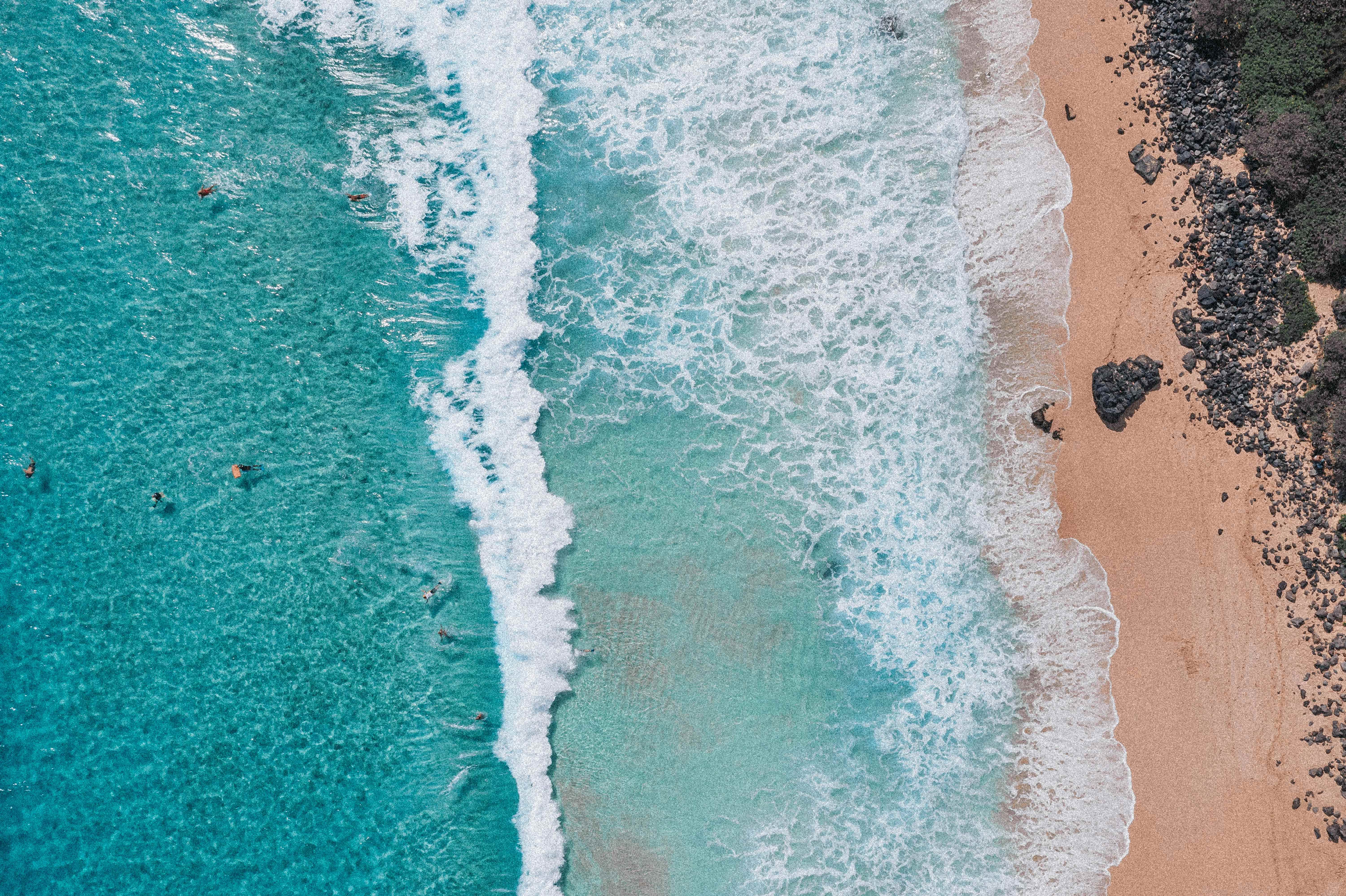 Aerial view of turquoise ocean waves meeting sandy beach