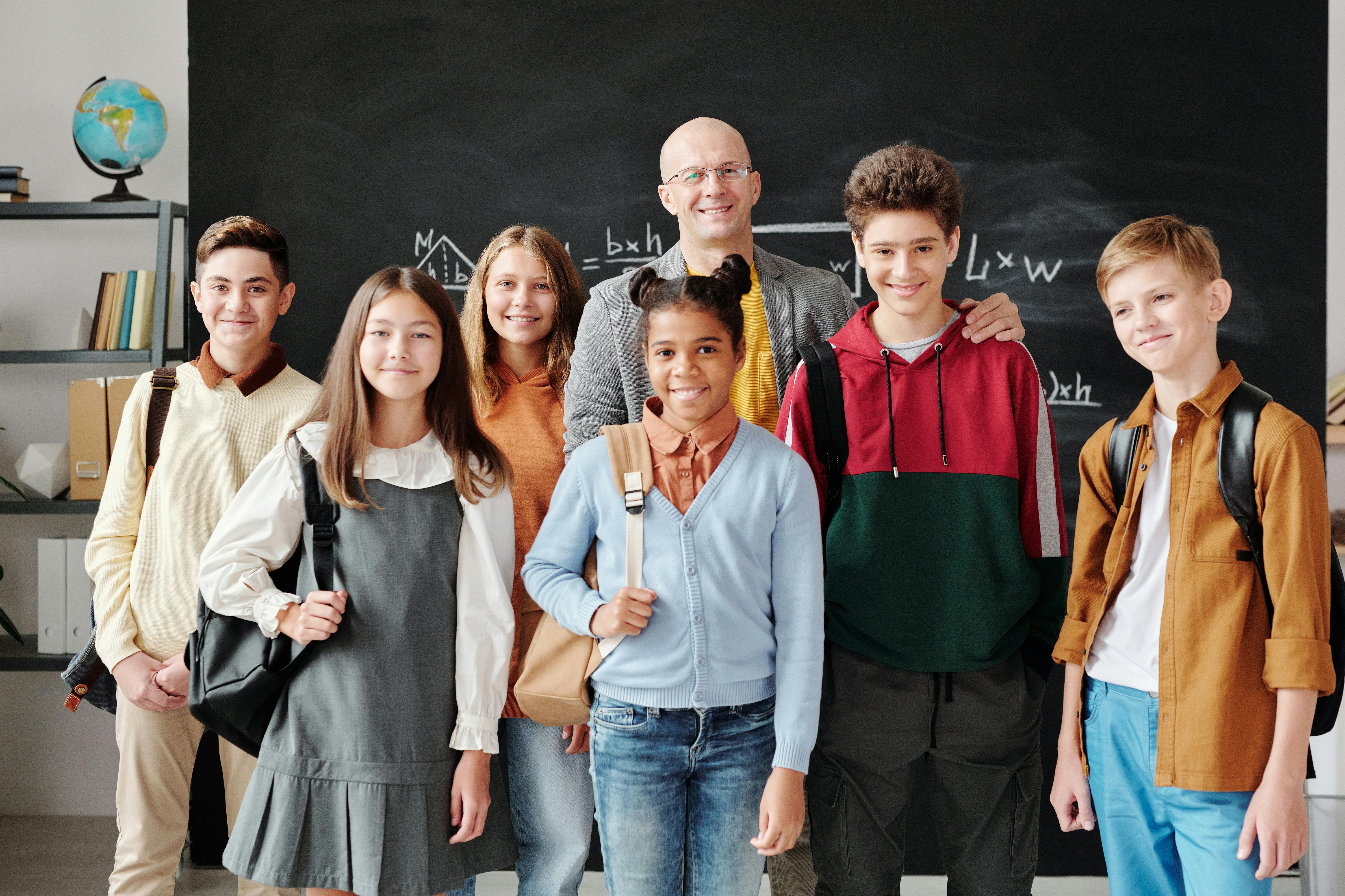 Happy students with teacher in classroom