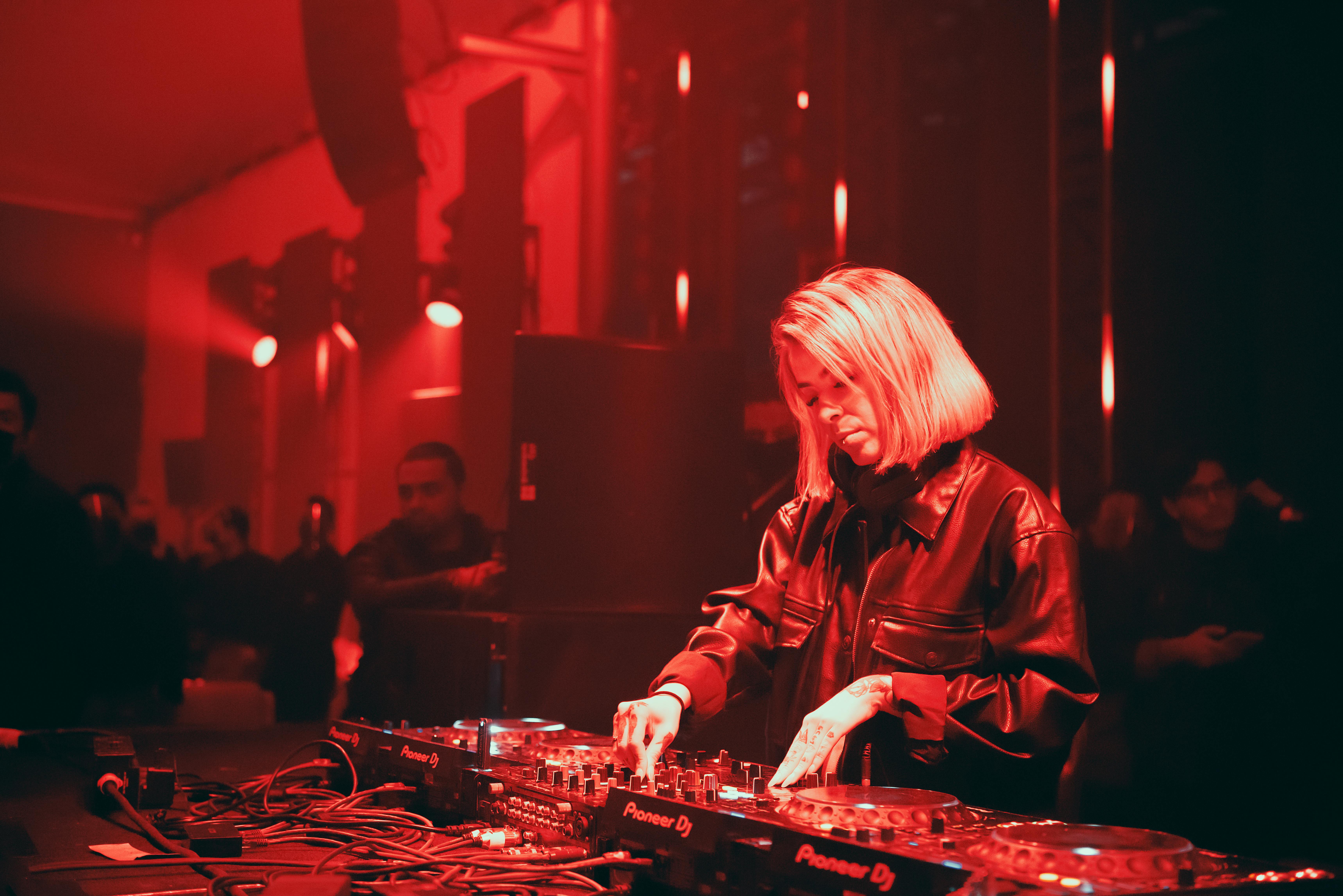 DJ mixing on Pioneer decks in red club lighting