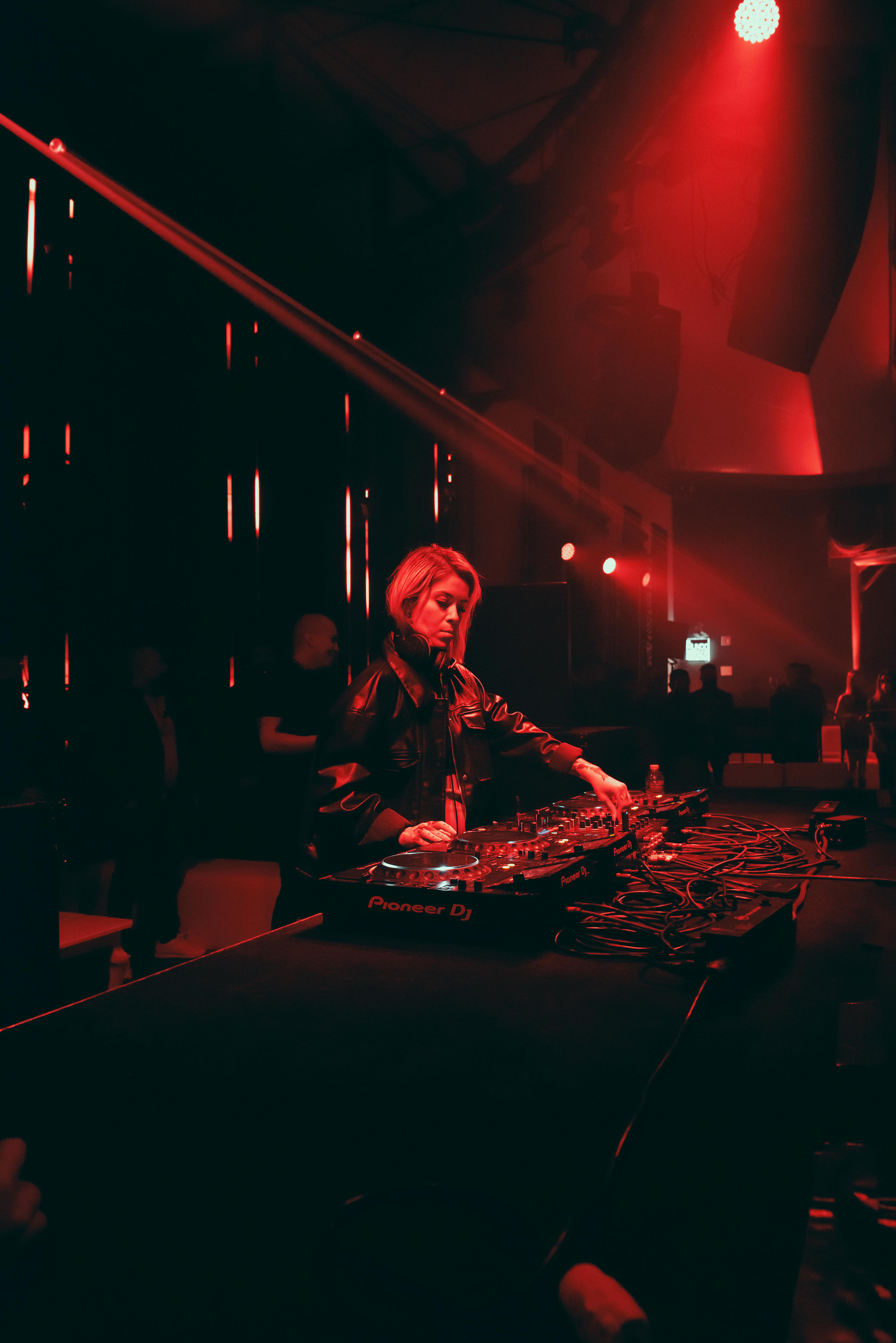 DJ performing with Pioneer decks in red lighting