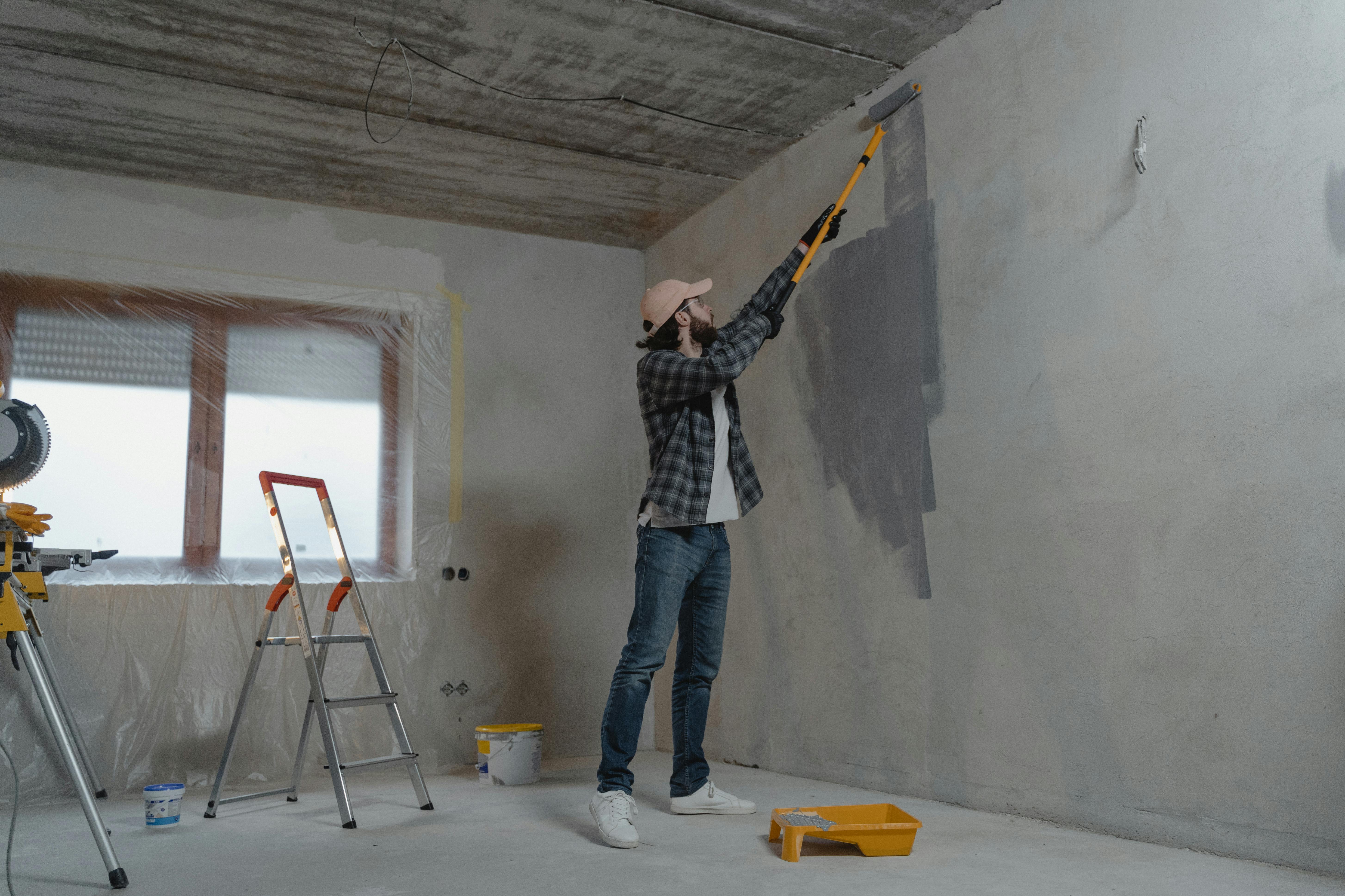 Contractor rolling gray paint onto an interior wall