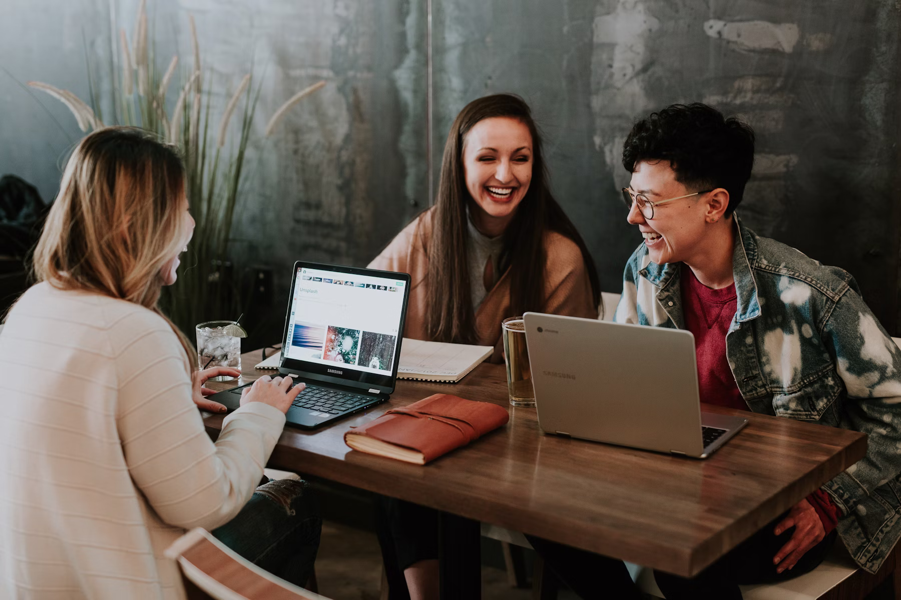 A large diverse group of professionals of different ethnicities, genders, and ages laughing and collaborating around a conference table
