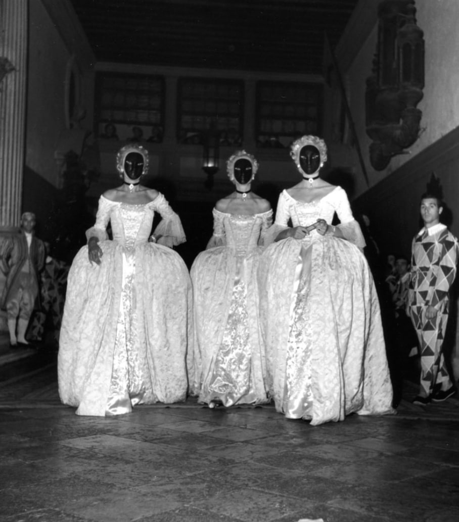 Three masked models in baroque ball gowns at a Jacques Fath theatrical masquerade