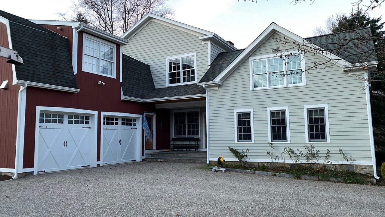 White gutter system on two-tone colonial with red barn and white carriage-house garage — Westchester County