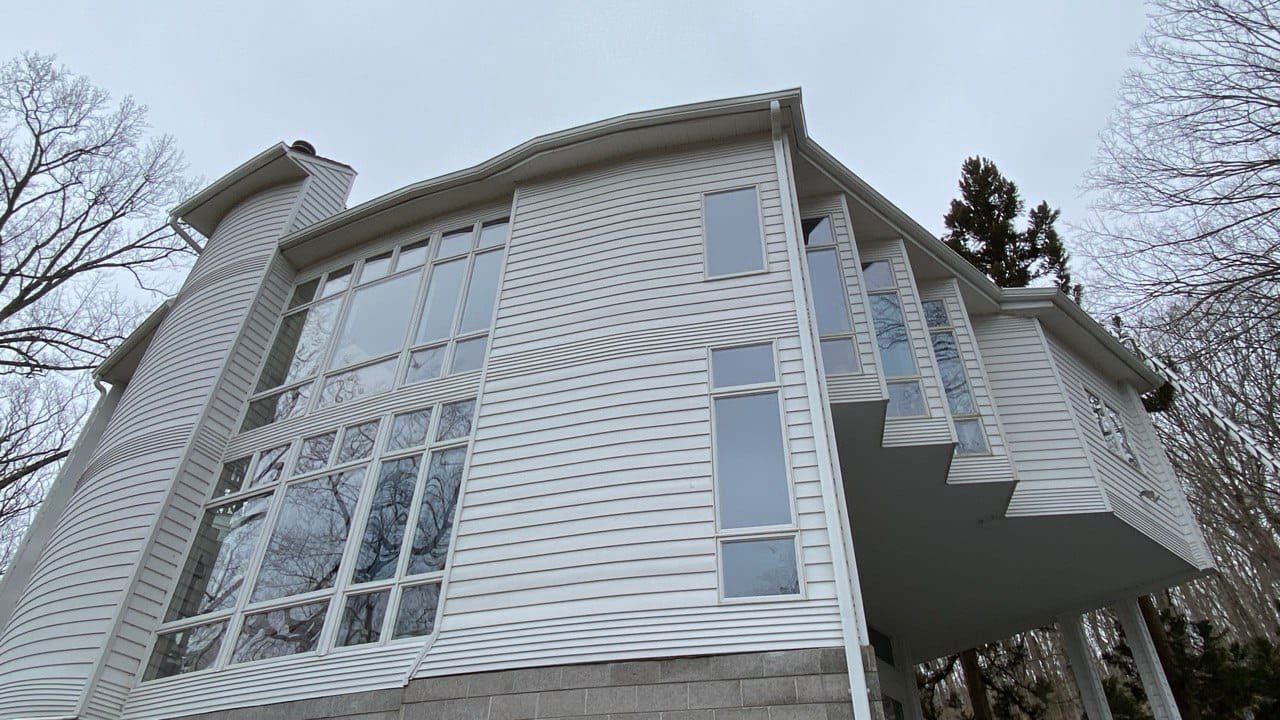 New seamless white gutters on curved contemporary home with floor-to-ceiling windows — Connecticut