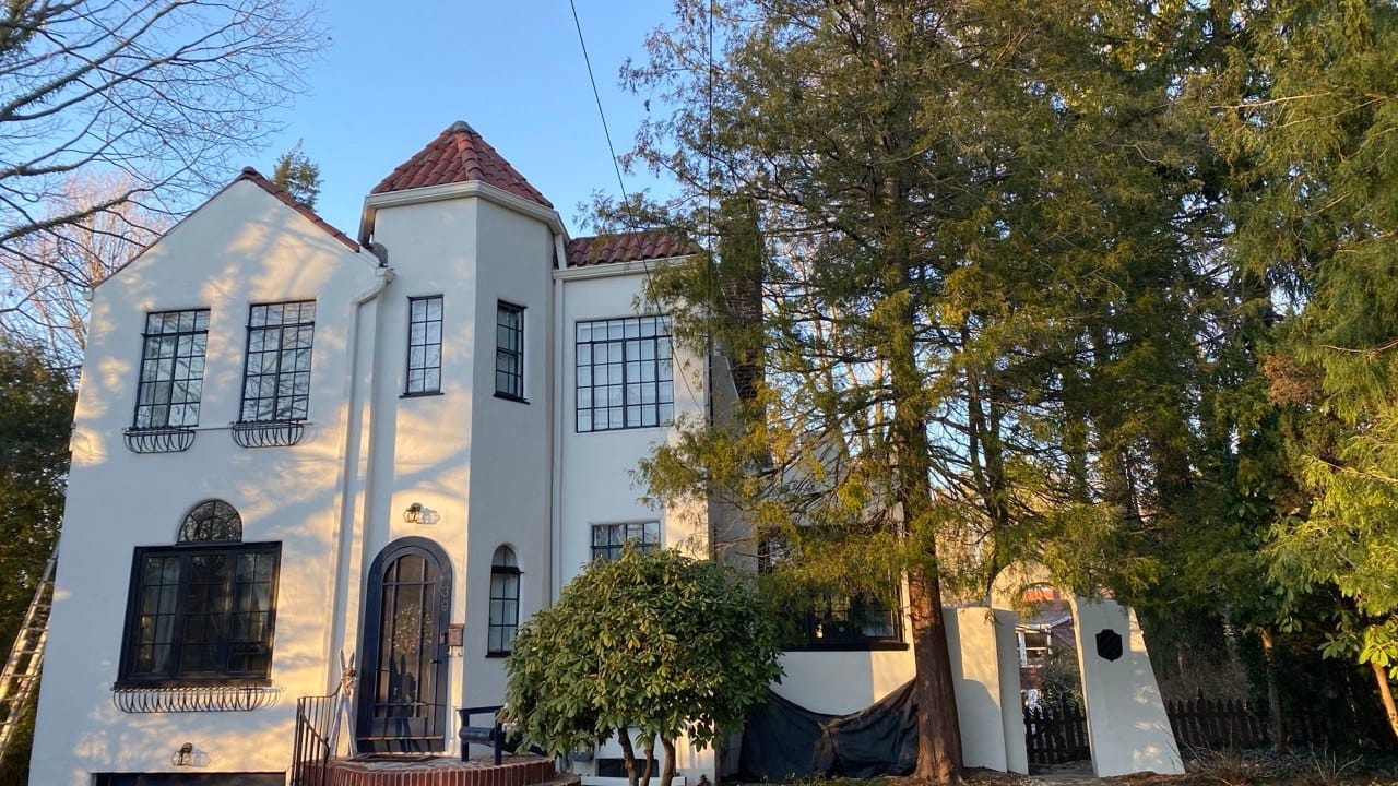Gutter installation on white Spanish-style home with terracotta tile tower and arched entry — Connecticut