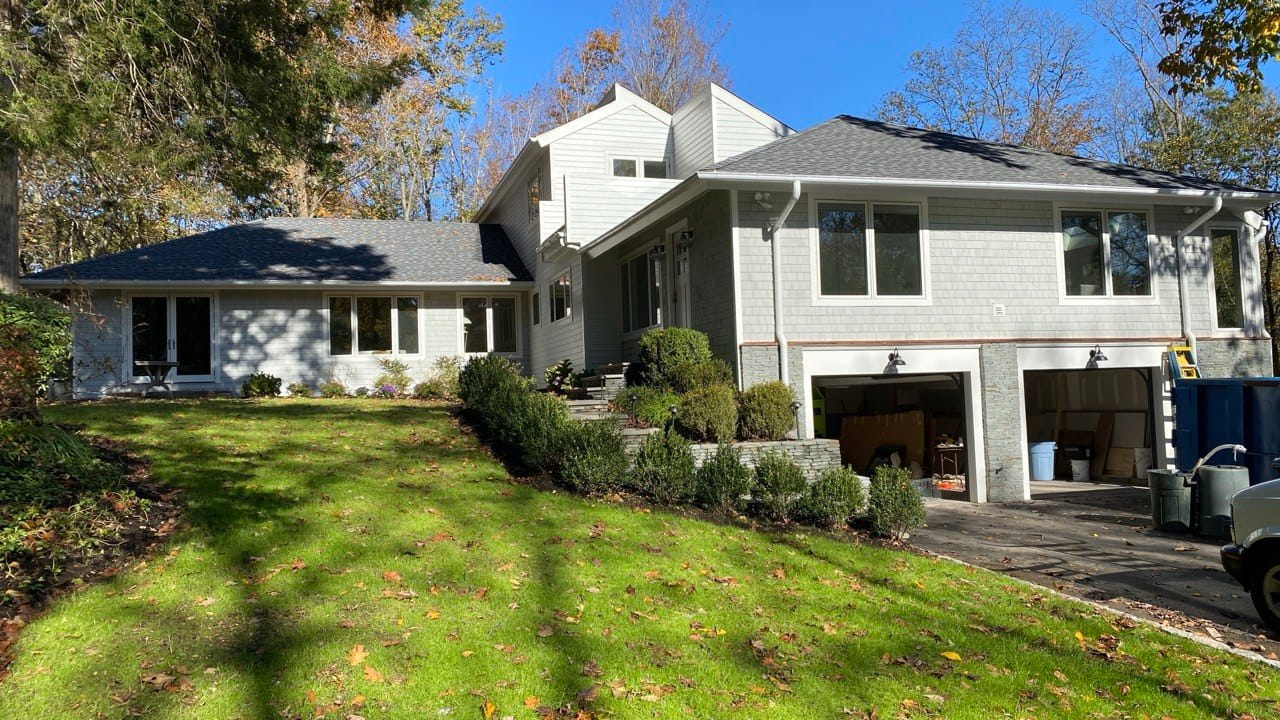 New seamless gutter installed on gray shingle cape with attached garage — autumn Connecticut