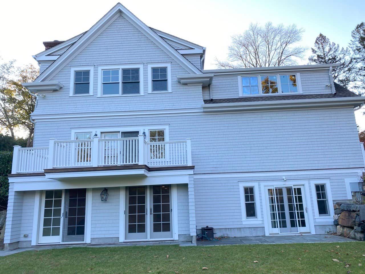 Gutter installation on gray shingle home with balcony
