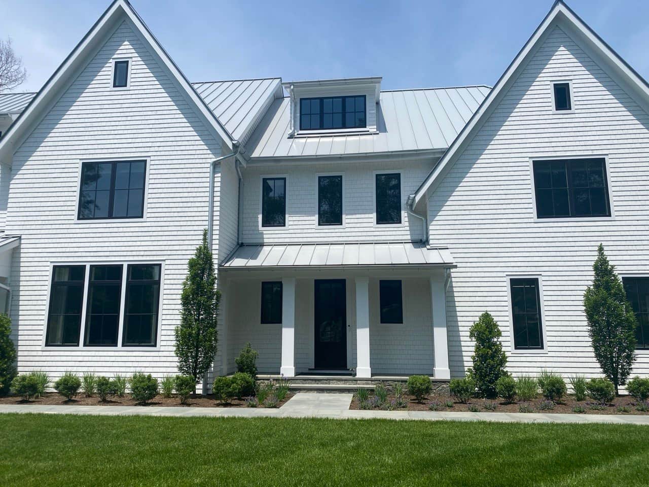 New gutter installation on white home with metal roof