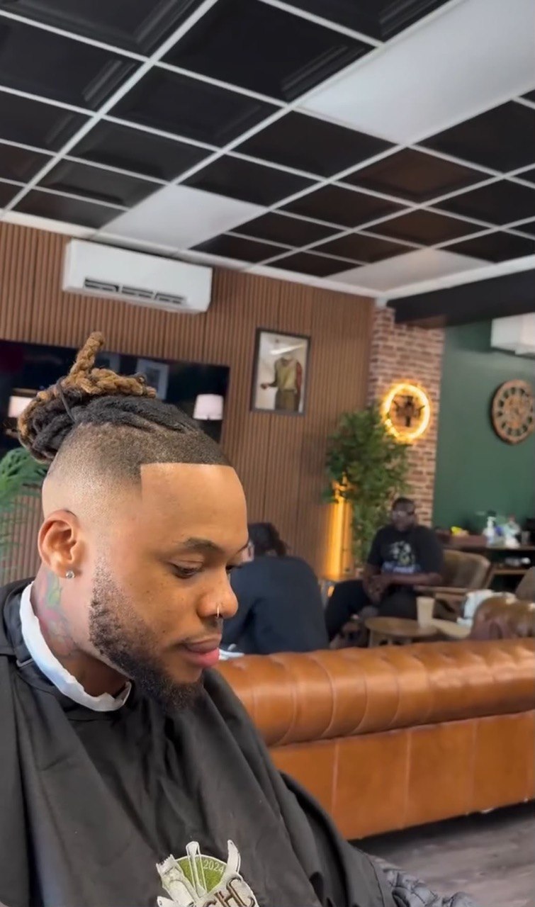 High-top fade with locs and clean lineup in a luxury lounge