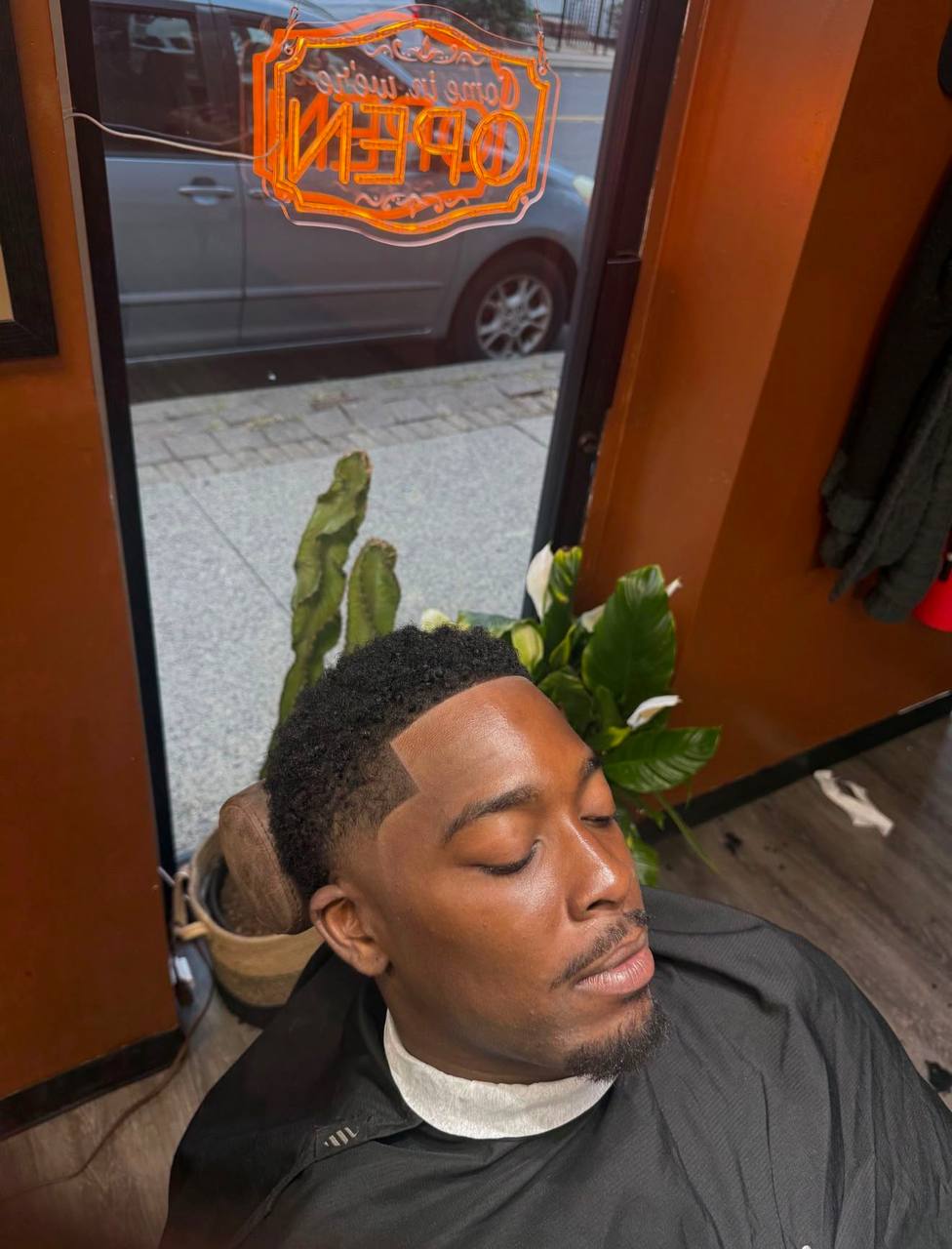 Elegant fade with neon barber shop window in background