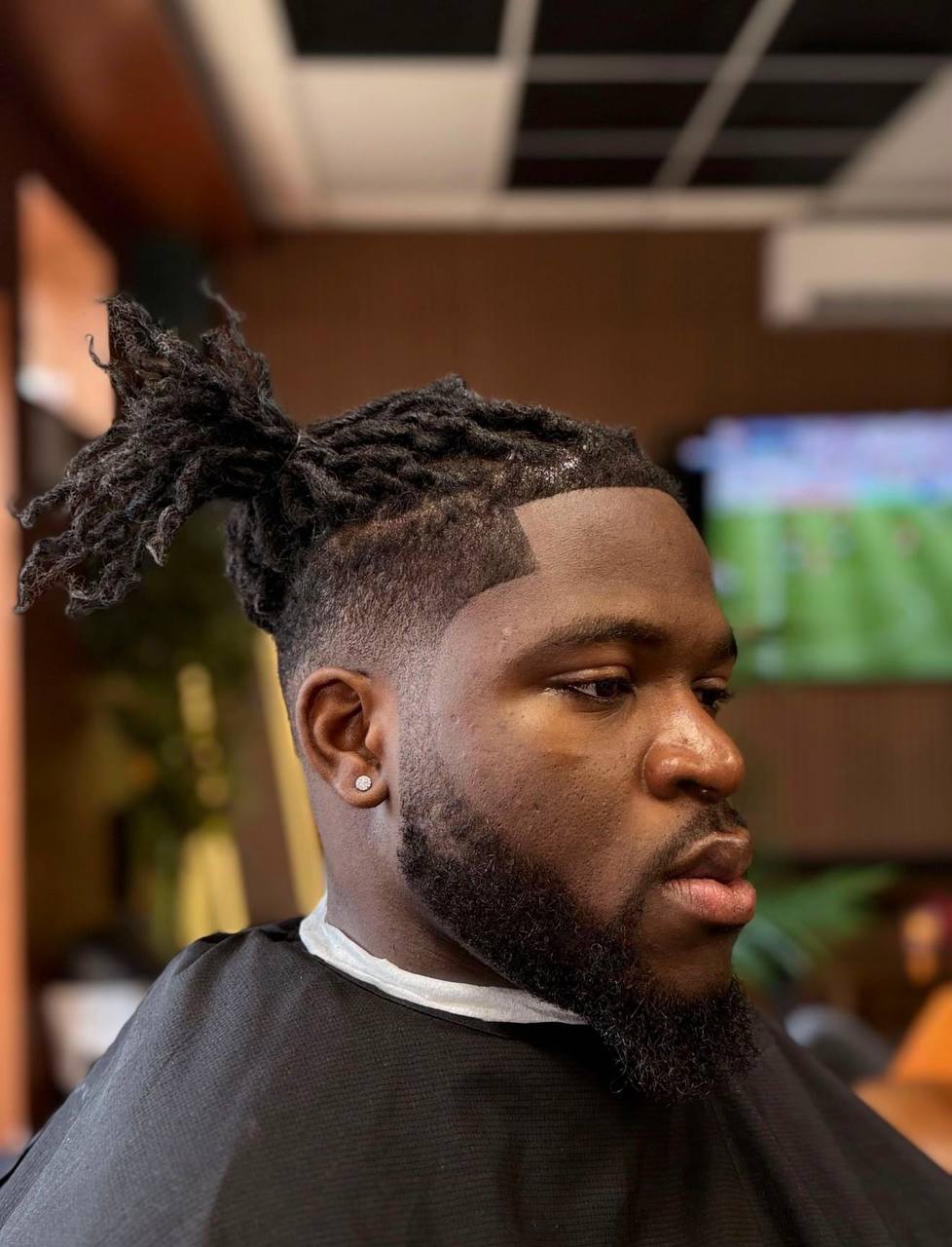 Profile shot of sharp fade with braids in professional setting