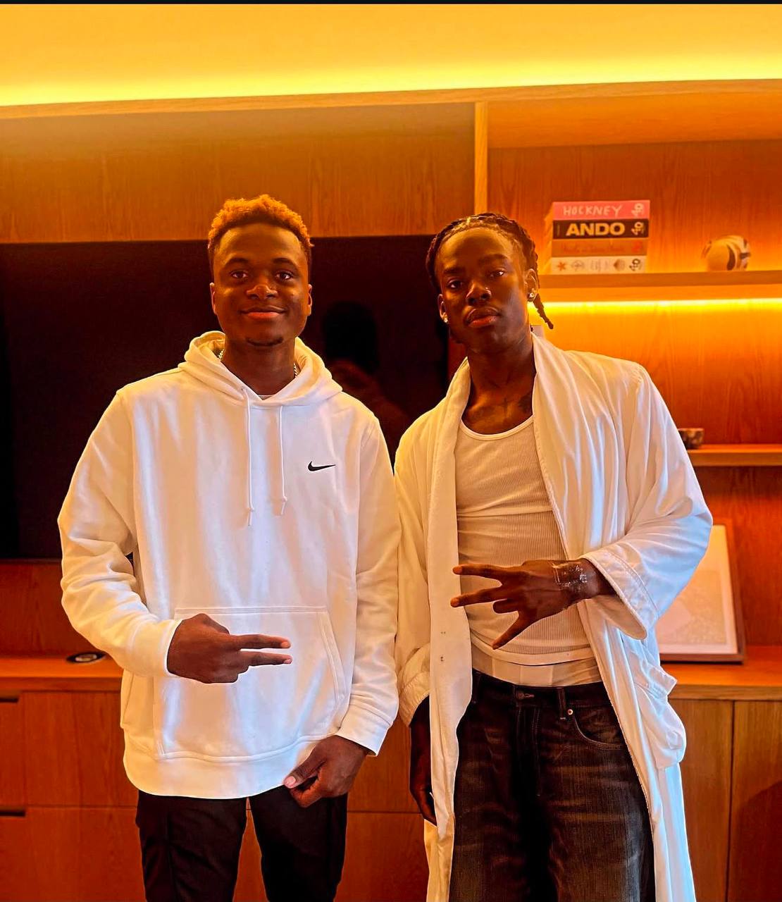 Two clients in modern orange-lit luxury barber lounge