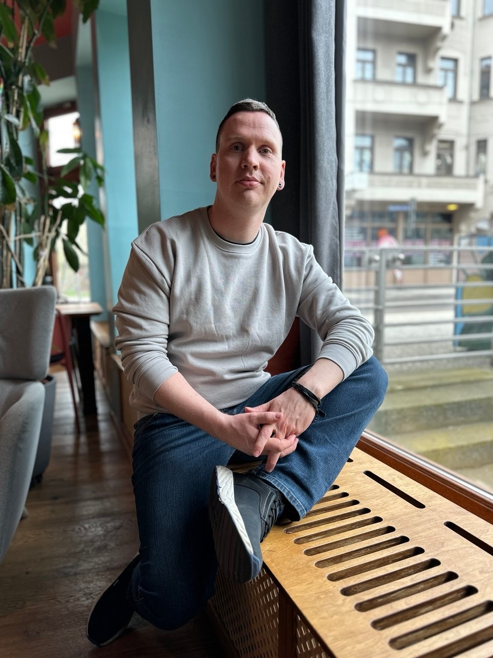 Matthias Walter sitzt in einem Café am Fenster auf einer Bank