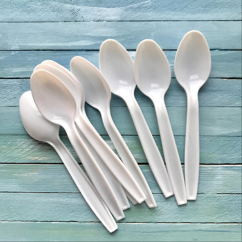 A fanned-out pile of white plastic spoons on a blue painted wooden surface