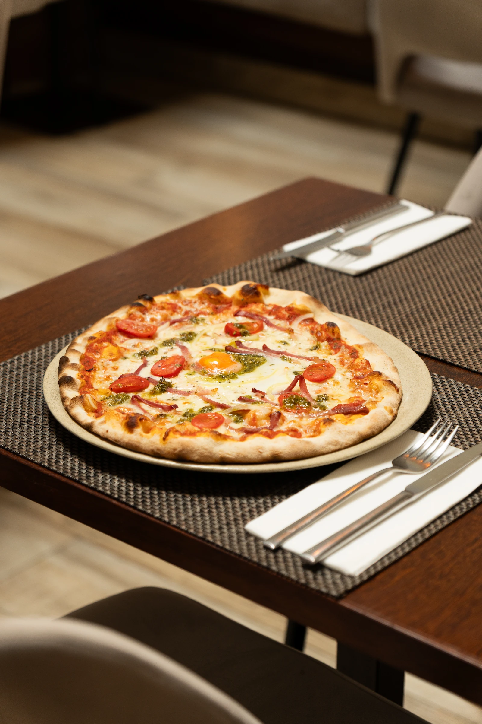 Pizza artesanal servida em prato branco com talheres