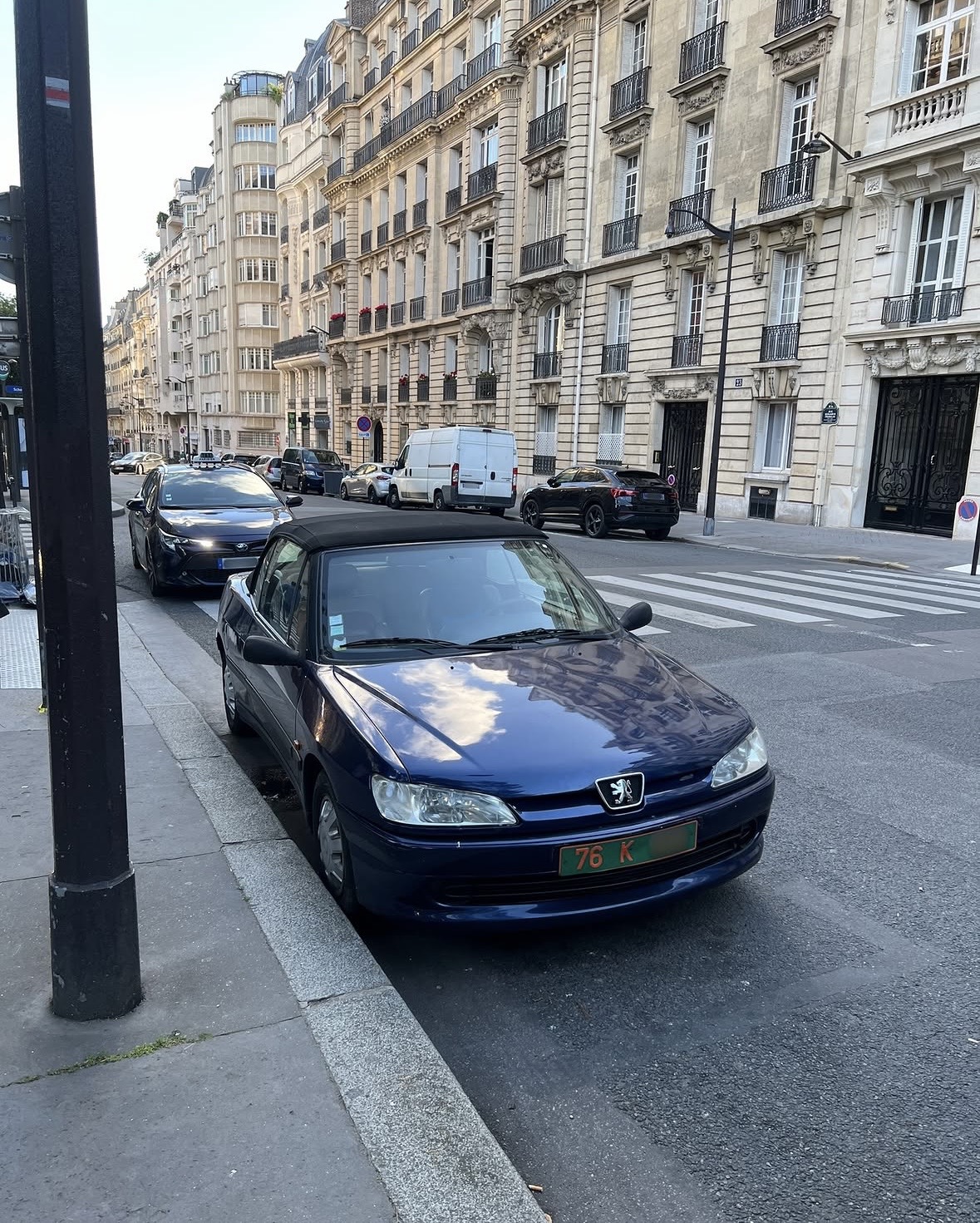 Plaque 76 K — Maroc, personnel technique à Paris Plaque diplomatique verte 76 K sur une Peugeot 306 cabriolet bleue garée dans une rue parisienne — code 76 Maroc