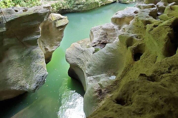 Emerald green water flowing through carved limestone canyon at Charco Azul